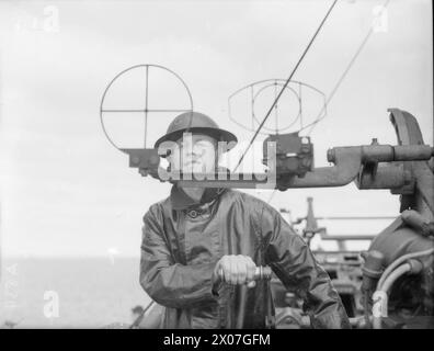 In September 1940, officers and men of HMS Rodney are shown aboard the battleship, including a crew member operating a .5-inch gun sight. Stock Photo