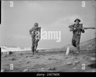 LUXEMBOURG TROOPS FIGHT WITH UNITED NATIONS: TRAINING WITH THE BELGIAN ARMY IN ENGLAND, UK, 1943 - Two soldiers from Luxembourg run along the sand during a bayonet charge as part of a training session with the Belgian Army along the coast, somewhere in England Stock Photo