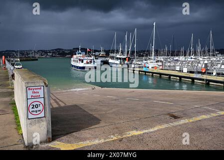 Sunshine and dark clouds over boats in Torquay harbour, as rain approaches and Western Lady Ferry Dittisham Princess departs for Brixham. Stock Photo