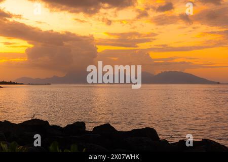 The island of Mo'orea is seen in the distance under a spectacular sunset from the capital of French Polynesia, Papeete, on the South Pacific island of Stock Photo