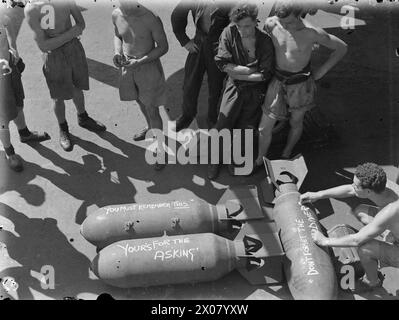 THEY BATTERED SURABAYA. 5 TO 27 MAY 1944, ON BOARD THE AIRCRAFT CARRIER HMS ILLUSTRIOUS IN THE INDIAN OCEAN. SCENES ON BOARD THE ILLUSTRIOUS WHEN AN AIRSTRIKE BY BRITISH, AMERICAN, AUSTRALIAN, FRENCH, AND DUTCH UNITS, WAS CARRIED OUT AGAINST THE JAPANESE-HELD NAVAL BASE. - A rigger writes some slogans for Tojo on the bombs to be delivered Stock Photo