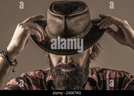 Cowboy style. Handsome young man adjusting his cowboy hat. Cowboys in hat. Handsome bearded macho. Man unshaven cowboys. American cowboy. Leather Stock Photo