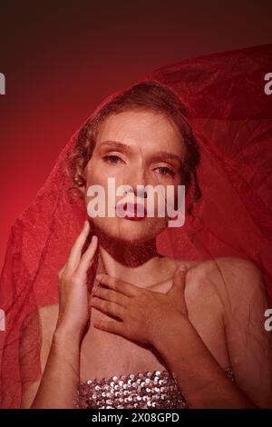 A young woman exudes classic beauty as she poses in a studio, her head adorned with a veil. Stock Photo