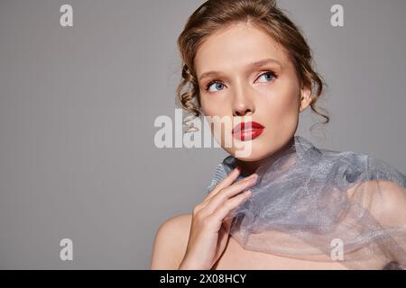 A young woman exudes classic beauty as she poses in a studio, wearing a veil and striking red lipstick. Stock Photo