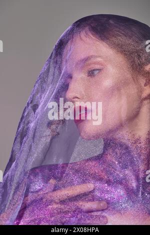 A young woman exudes classic beauty in a studio setting, wearing a delicate grey veil on her head. Stock Photo