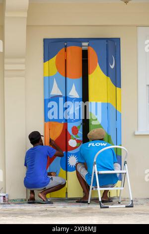 Two local men painting a colourful mural on a doorway, Port Elizabeth, Bequia Island, St Vincent & the Grenadines, Caribbean Stock Photo