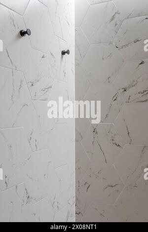 Elegant white marble textured tiles on a bathroom wall with modern hexagonal shapes Stock Photo