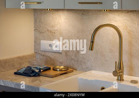 Elegant modern kitchen with a marble backsplash and gold faucet highlighting luxurious interior design Stock Photo