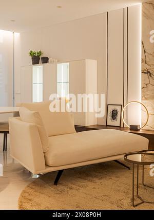 Contemporary living room featuring a beige sofa, marble walls, and simplistic decor, highlighting a sophisticated and minimalist design Stock Photo