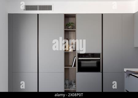 Modern kitchen interior featuring sleek grey cabinets and built-in appliances Stock Photo