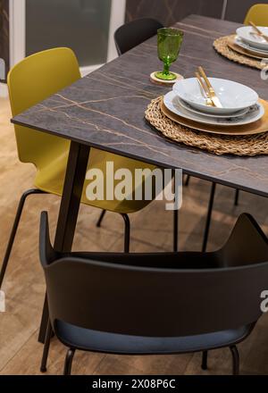 Modern dining room setup with yellow chairs and marble table set for dinner Stock Photo