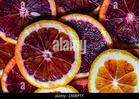 From above of vibrant close-up of freshly sliced Sicilian blood oranges and navel oranges, showcasing the rich color and juicy texture. Stock Photo