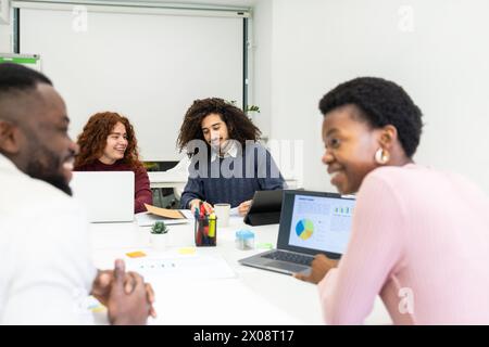 Diverse team of professionals engaged in a collaborative meeting with laptops and documents. Stock Photo
