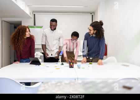A multiethnic group of professionals engages in a collaborative discussion around a white table in a bright modern office setting. Stock Photo