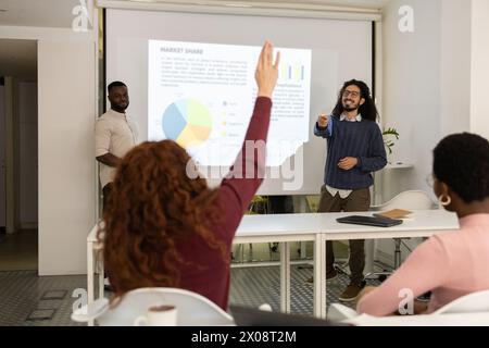 Diverse team in a business meeting with a man presenting data on a projector screen while colleagues look on. Stock Photo