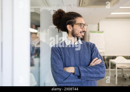 Confident ethnic man with glasses smiling and looking away in an office setting Stock Photo