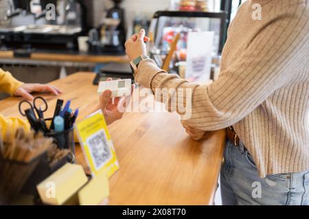Customer making a contactless payment with a smartwatch at a coffee counter. Stock Photo