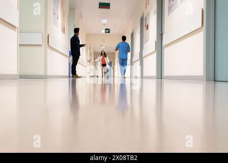 Female medic running in hall of hospital beneath people. Stock Photo