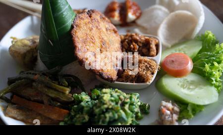 Traditional Balinese Nasi Campur with multiple dishes on white plate Stock Photo