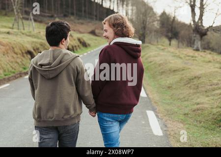 A loving couple walks hand in hand down a peaceful rural road, enjoying each other's company and the quiet of the countryside Stock Photo