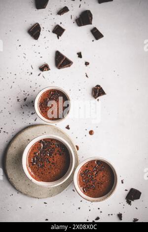 Top-down view of three chocolate lava cakes sprinkled with chocolate shards, elegantly presented on a white surface Stock Photo