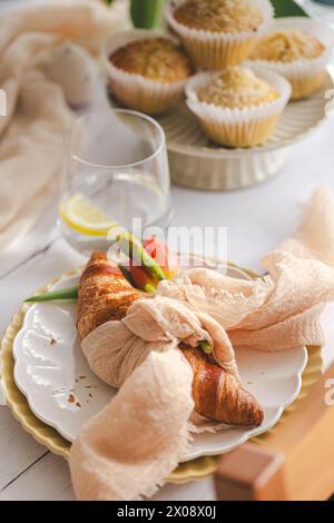 A cozy Easter brunch setting featuring freshly baked croissants, coconut muffins on a ceramic plate, with spring-inspired tableware and a hint of spri Stock Photo