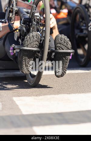 Cropped unrecognizable shot of a female handbike racer, showcasing her shoes on the pedals mid-competition. Stock Photo