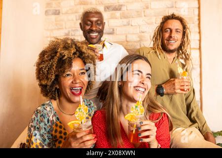 Group of cheerful friends enjoying colorful cocktails and sharing a laugh in a warm, inviting bar setting Stock Photo