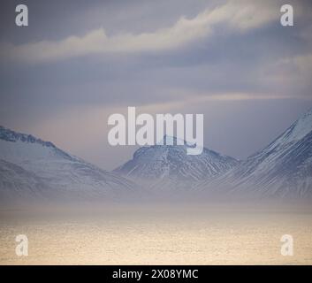 Misty Icelandic mountainscape with snow-covered peaks under a subtle sky Stock Photo