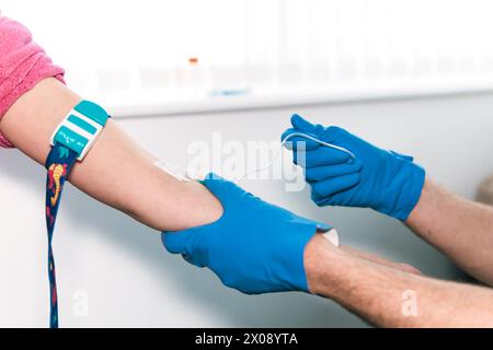 Focused healthcare anonymous professional adeptly inserts an IV catheter into a patient's vein during a medical procedure in a bright clinical setting Stock Photo