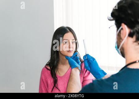 In a clinical setting, a doctor conducts a reflex test using a reflex hammer on a patient's knee to assess neurological function Stock Photo