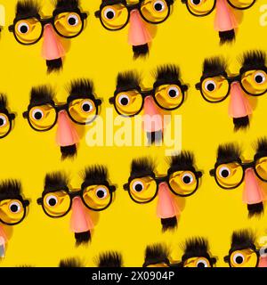 An array of comical fake glasses with noses, mustaches, and eyebrows against a vibrant yellow backdrop, creating a quirky pattern. Stock Photo