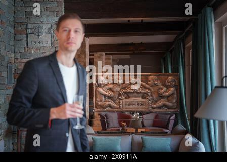 Luxury hotel scene with man in dark suit holding glass, Zermatt, Switzerland Stock Photo