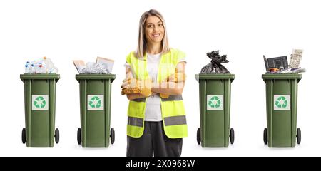 Female waste collector in a uniform and gloves posing in front of bins with recycling materials isolated on white background Stock Photo