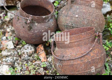 Three aged and ferrous iron pans. Kitchen utensils for cooking meals over a fireplace in a rural context. Stock Photo