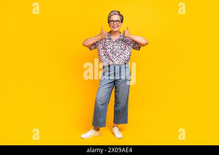 Full length photo of lovely senior lady show double thumbs up dressed stylish leopard print garment isolated on yellow color background Stock Photo