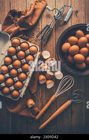 Fresh organic eggs with kitchen and baking utensils on wooden table Stock Photo