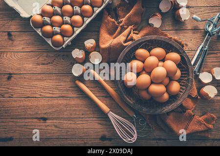 Fresh organic eggs with kitchen and baking utensils on wooden table Stock Photo