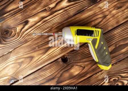 a cordless screwdriver. Cordless drill on a wooden background. DIY concept Stock Photo