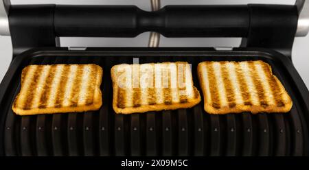 Cooking toasted bread on an electric grill. Toast bread concept. Stock Photo