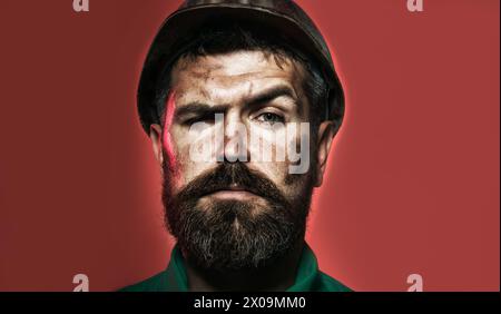 Closeup portrait serious male architect, builder engineer with beard in uniform and construction protective helmet. Bearded male worker in safety hard Stock Photo