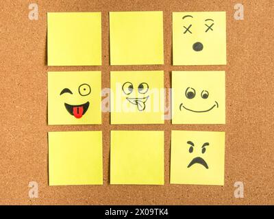 cork board with colorful post its representing various emoticons with various emotions communication concept Stock Photo
