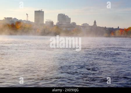 Manchester, New Hampshire USA on a foggy autumn day from the along the Merrimack River. Stock Photo