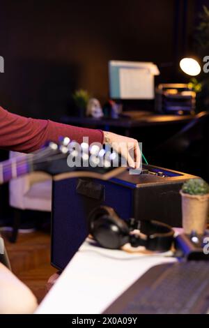 Sound producer adjusting volume levels on home studio amplifier before recording guitar tunes for mixing and mastering session. Male composer creating a new song with stereo gear. Close up. Stock Photo
