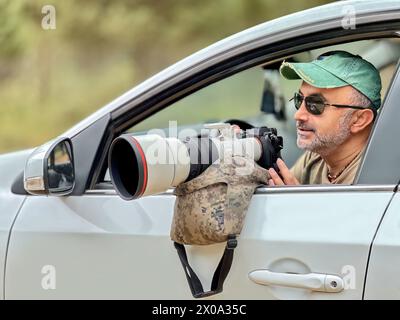 Nature photographer photographing birds through a car window. Bird Photographer. Ornithology Stock Photo