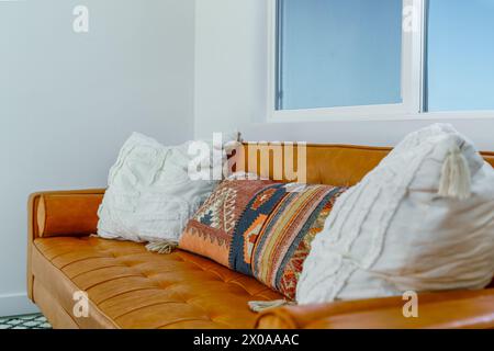Brown leather couch and decorative southwestern pillows in a modern bohemian desert home Stock Photo