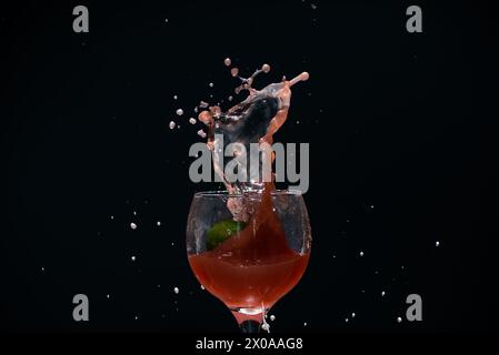 Splashes in a glass cup with guava juice inside. Isolated on dark background. Stock Photo