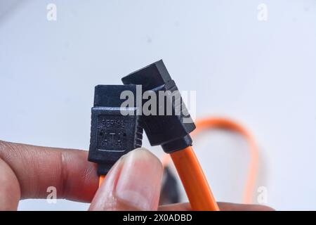 Close up orange Serial ATA(SATA) cable connected to computer motherboard. SATA is an interface for transferring data between a motherboard and mass st Stock Photo