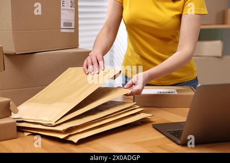 Parcel packing. Post office worker with parcels at wooden table indoors, closeup Stock Photo