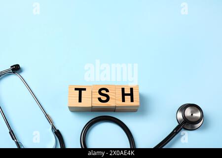 Endocrinology. Stethoscope and wooden cubes with thyroid hormones on light blue background. Space for text Stock Photo